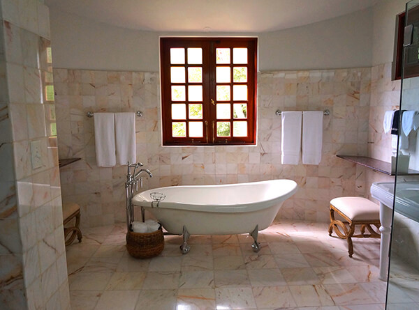 white bathtub in middle of tile wall and tile floor covered bathroom